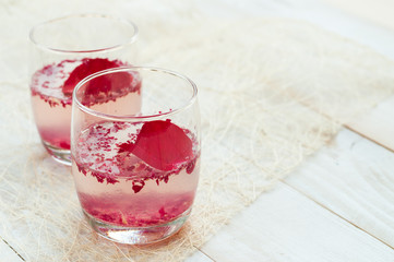 Pink Cocktail with fresh rose petals on wooden table