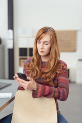 frau im büro tippt auf ihr mobiltelefon
