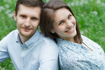 Obraz premium Loving couple in the park in the grass and dandelions. They were
