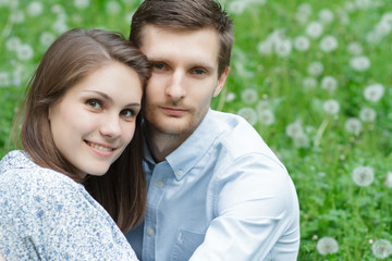 Obraz premium Loving couple in the park in the grass and dandelions
