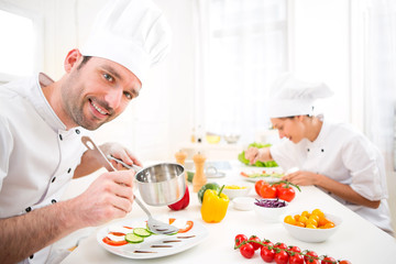 Young attractive professional chef cooking in his kitchen