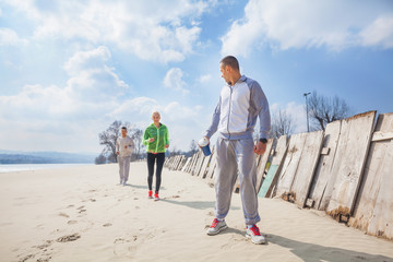 Three young people jogging on the beach. 