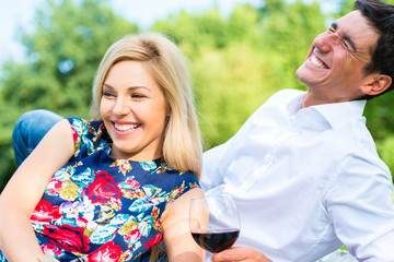 Paar trinkt Rotwein im Gras in Sommer Park