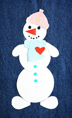 Handmade snowman on dark jeans background