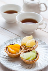Fruit tart with tea on wooden board