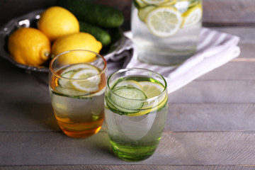 Fresh water with lemon and cucumber in glassware on wooden background