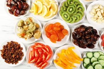 Different products on saucers on wooden table, top view