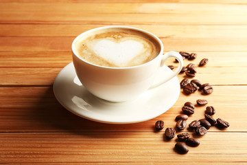 Cup of coffee latte art with grains on wooden background