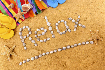 The word relax written with seashells on a summer beach sand background with towel star fish and sea shell holiday vacation photo