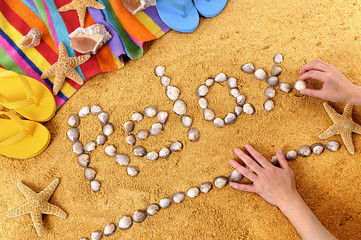 Fototapeta na wymiar The word relax written with seashells on a summer beach sand background with towel star fish and sea shell holiday vacation photo