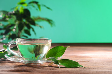 Cup of green tea on table on green background