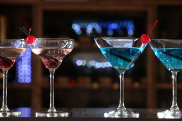 Glasses of cocktails on bar background