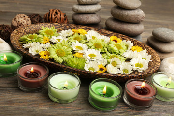 Candles with flowers on plate on table close up