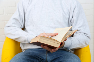 Young man reading book, close-up, on light background