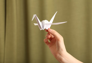 Female hand with paper crane on blurred background