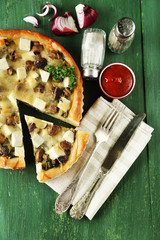 Cheese pie with mushrooms, herbs and sour creme, on napkin, on color wooden table background