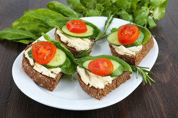 Delicious sandwiches with vegetables and greens on plate close up