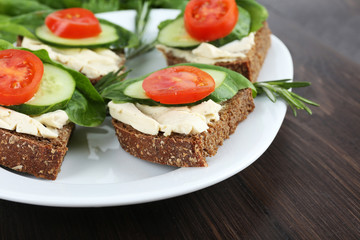 Delicious sandwiches with vegetables and greens on plate close up