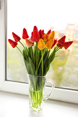 Bouquet of fresh tulips on windowsill background