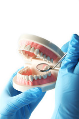 Fototapeta na wymiar White fake teeth in hand of dentist, isolated on white