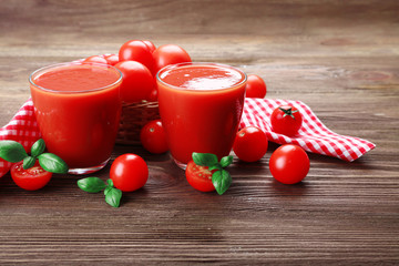 Glasses of tomato juice with vegetables on wooden background