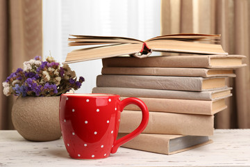 Books, cup and plant on wooden table, closeup