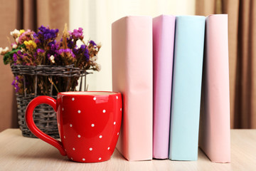 Books, cup and plant on wooden table, closeup