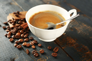 Cup of coffee with beans on table, closeup
