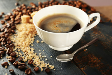Cup of coffee with beans on table, closeup