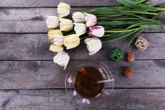 Cup of herbal tea with tulips on wooden table, top view