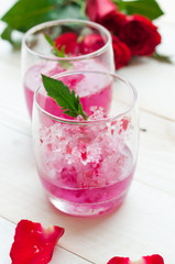 Pink Cocktail with fresh rose petals on wooden table