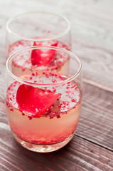Pink Cocktail with fresh rose petals on wooden table