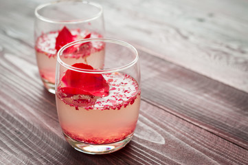 Pink Cocktail with fresh rose petals on wooden table