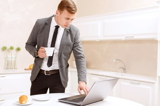 Businessman standing with cup of coffee using computer 