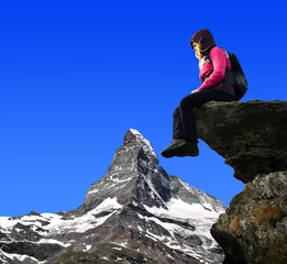 Papier Peint photo Cervin Girl sitting on a rock, in the background Matterhorn