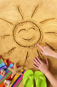 Summer beach smiling sun happy smiley face drawing drawn in sand with accessories holiday vacation photo vertical