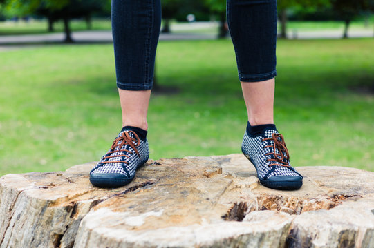 Feet of young woman standing on tree trunk