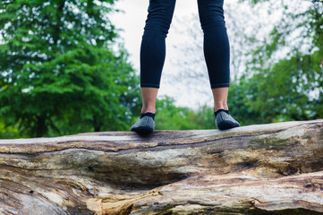 Young woman standing on a tree trunk in park