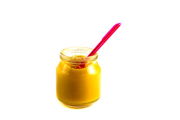 Baby fruit puree in the pot with a plastic spoon