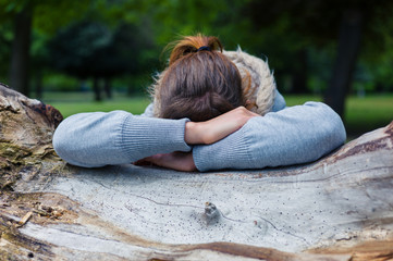 Sad woman resting on tree trunk