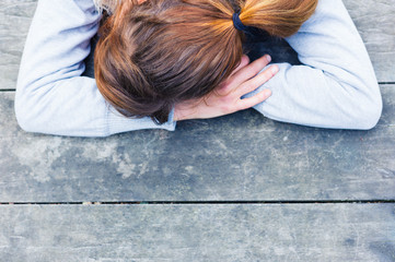 Sad young woman at table in park