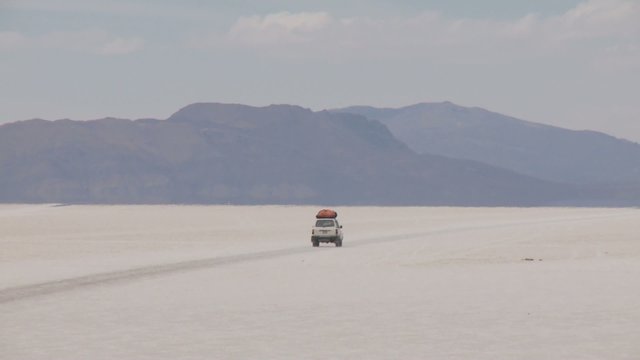 SUV on salt flat Salar de Uyuni in Andes of Bolivia