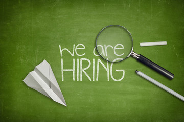 We are hiring concept on green blackboard with magnifying glass