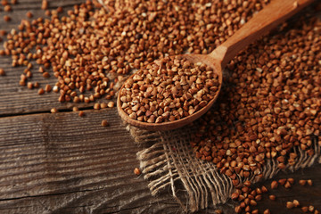 Buckwheat in a spoon on brown wooden background