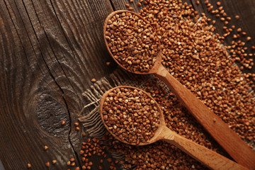 Buckwheat in a spoon on brown wooden background