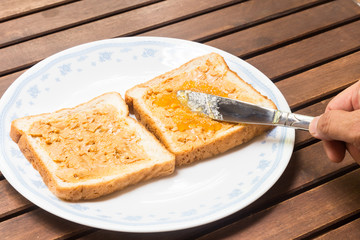 Spreading peanut butter and jelly onto wholemeal bread