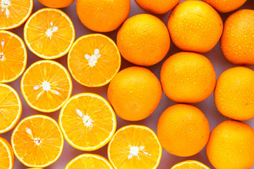 A closeup of a pile of oranges sliced and whole