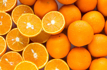A closeup of a pile of oranges sliced and whole