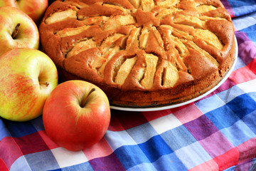 Freshly baked apple pie with apples in the background.