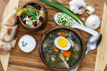 Sorrel soup in wooden bowl with egg and salad